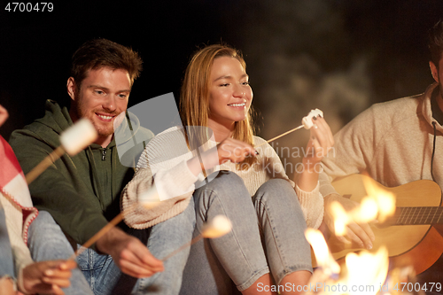 Image of friends roasting marshmallow and playing guitar