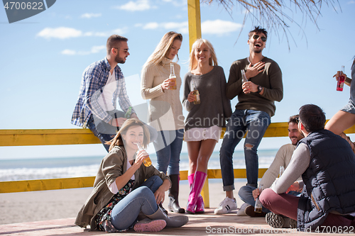 Image of Group of friends having fun on autumn day at beach