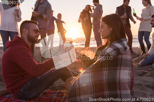 Image of Couple enjoying with friends at sunset on the beach