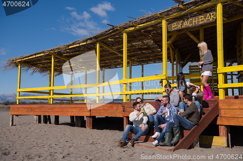 Image of Group of friends having fun on autumn day at beach