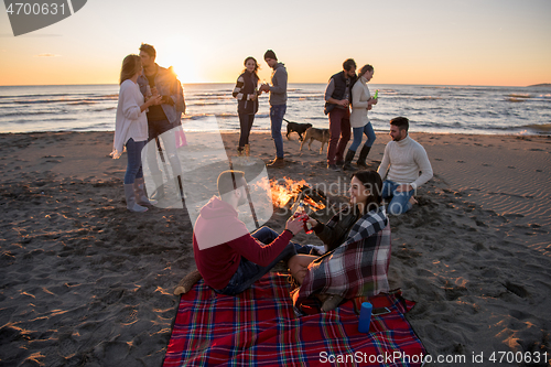 Image of Couple enjoying with friends at sunset on the beach