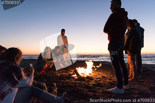 Image of Friends having fun at beach on autumn day