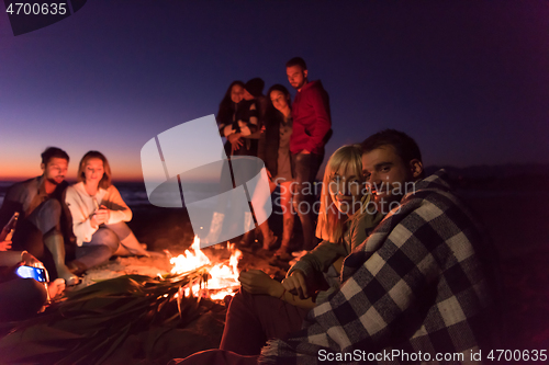 Image of Couple enjoying with friends at sunset on the beach