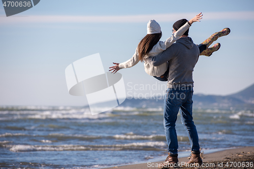 Image of Loving young couple on a beach at autumn sunny day