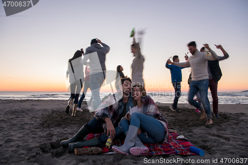 Image of Couple enjoying with friends at sunset on the beach