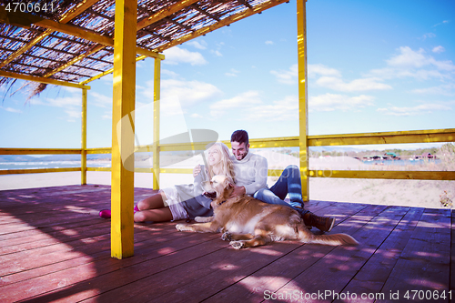 Image of Couple with dog enjoying time on beach