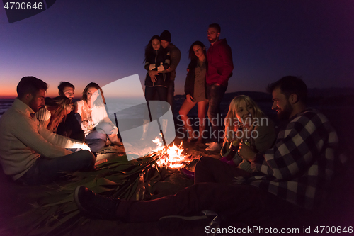 Image of Couple enjoying with friends at sunset on the beach