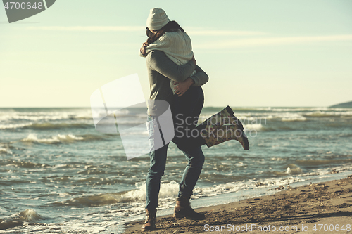 Image of Loving young couple on a beach at autumn sunny day