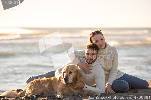 Image of Couple with dog enjoying time on beach