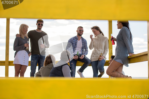 Image of Group of friends having fun on autumn day at beach