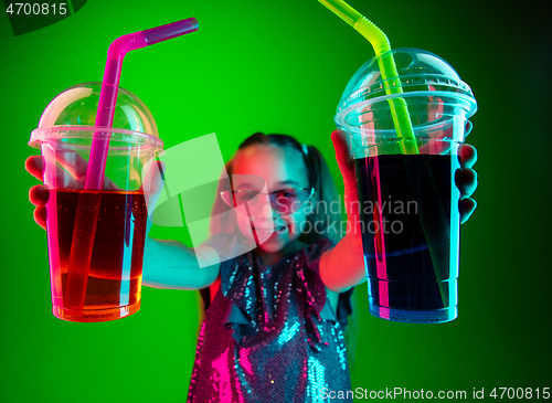 Image of The happy teen girl standing and smiling against green lights background.