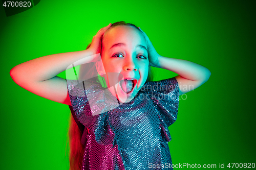 Image of Beautiful teen girl looking suprised isolated on green