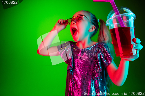 Image of The happy teen girl standing and smiling against green lights background.