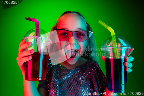 Image of The happy teen girl standing and smiling against green lights background.