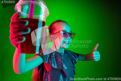 Image of The happy teen girl standing and smiling against green lights background.