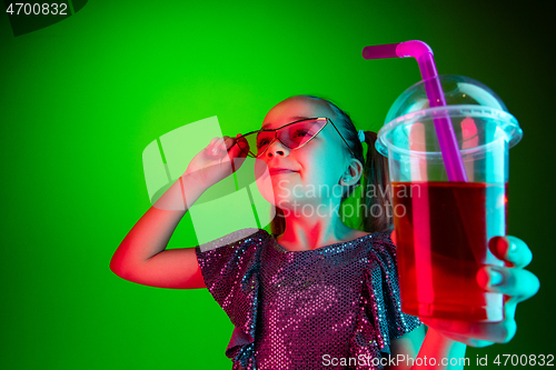 Image of The happy teen girl standing and smiling against green lights background.