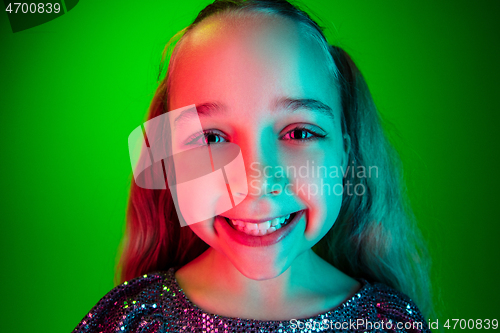 Image of The happy teen girl standing and smiling against green lights background.