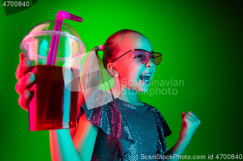 Image of The happy teen girl standing and smiling against green lights background.