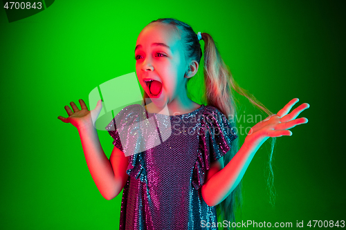 Image of Beautiful teen girl looking suprised isolated on green