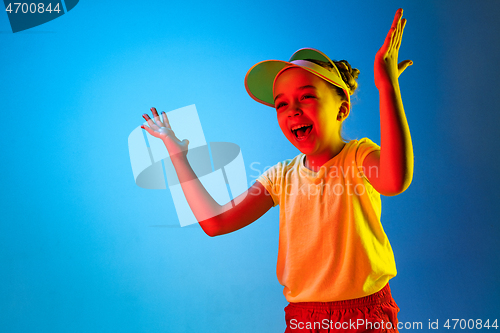 Image of The happy teen girl standing and smiling against blue background.