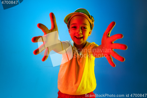 Image of The happy teen girl standing and smiling against blue background.