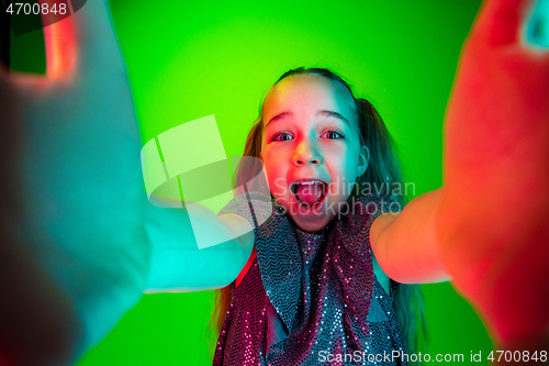 Image of The happy teen girl standing and smiling against green lights background.
