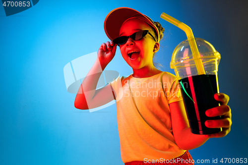 Image of The happy teen girl standing and smiling against blue background.