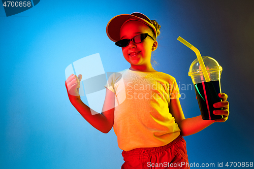 Image of The happy teen girl standing and smiling against blue background.