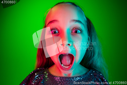 Image of Beautiful teen girl looking suprised isolated on green