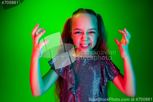 Image of Portrait of angry teen girl over green studio background