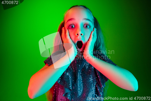 Image of Beautiful teen girl looking suprised isolated on green