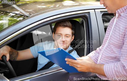 Image of car driving instructor with clipboard and driver