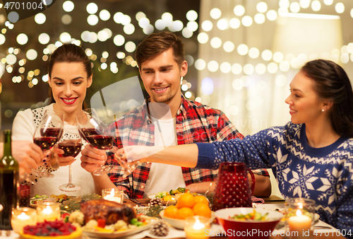 Image of happy friends drinking red wine at christmas party