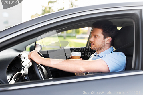 Image of tired man driving car with takeaway coffee