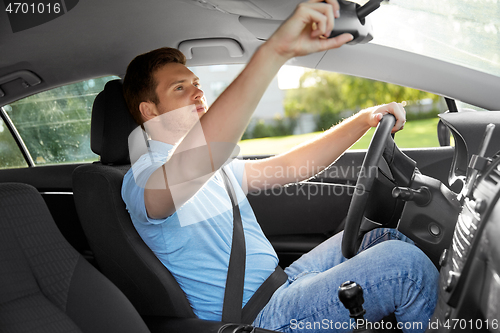 Image of man or car driver adjusting mirror