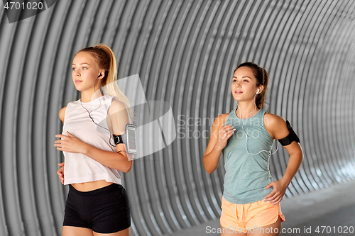 Image of young women with earphones and smartphones running