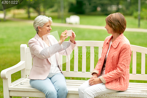 Image of senior woman photographing her friend at park