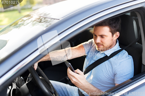 Image of man driving car and using smartphone