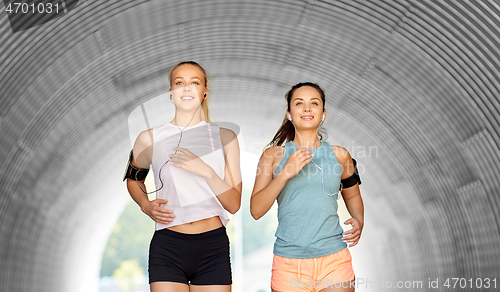 Image of young women with earphones and smartphones running