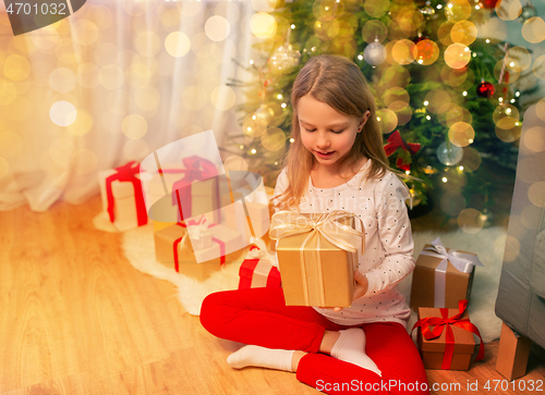 Image of smiling girl with christmas gift at home