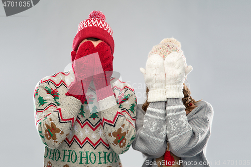 Image of couple in ugly sweaters and mittens on christmas