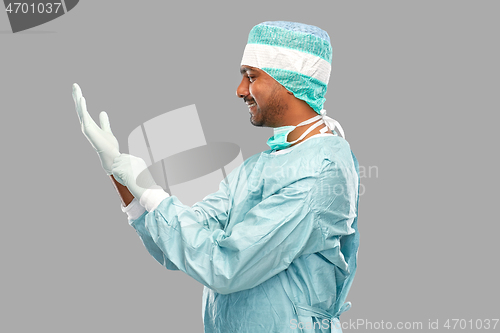 Image of indian male doctor or surgeon putting glove on