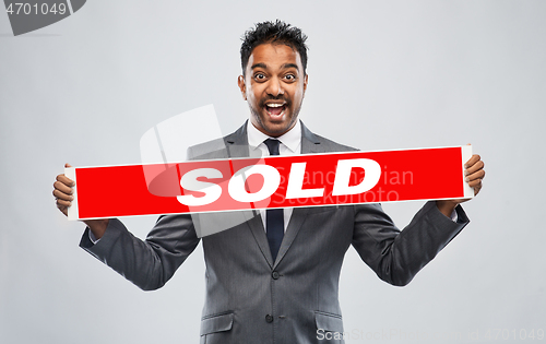 Image of happy indian male realtor with red sold banner
