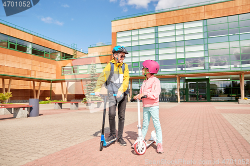 Image of happy school children with backpacks and scooters