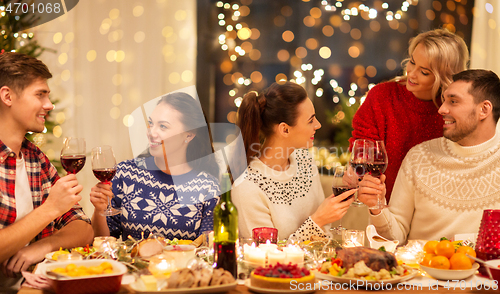 Image of happy friends drinking red wine at christmas party