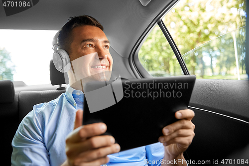 Image of passenger with headphones using tablet pc in car