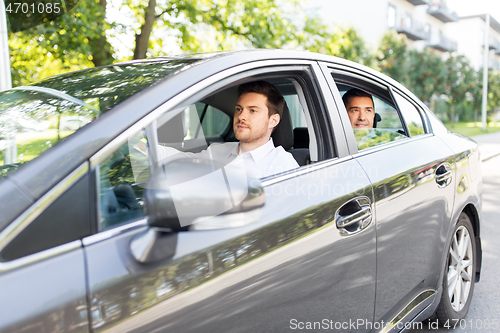 Image of male driver driving car with passenger