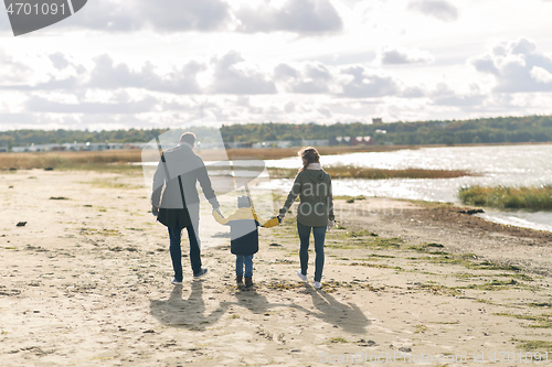 Image of happy family walking along autumn beach