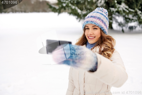 Image of woman taking selfie by smartphone in winter