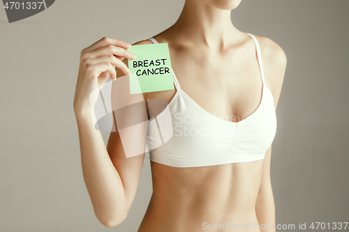 Image of Woman health. Female model holding card near breast